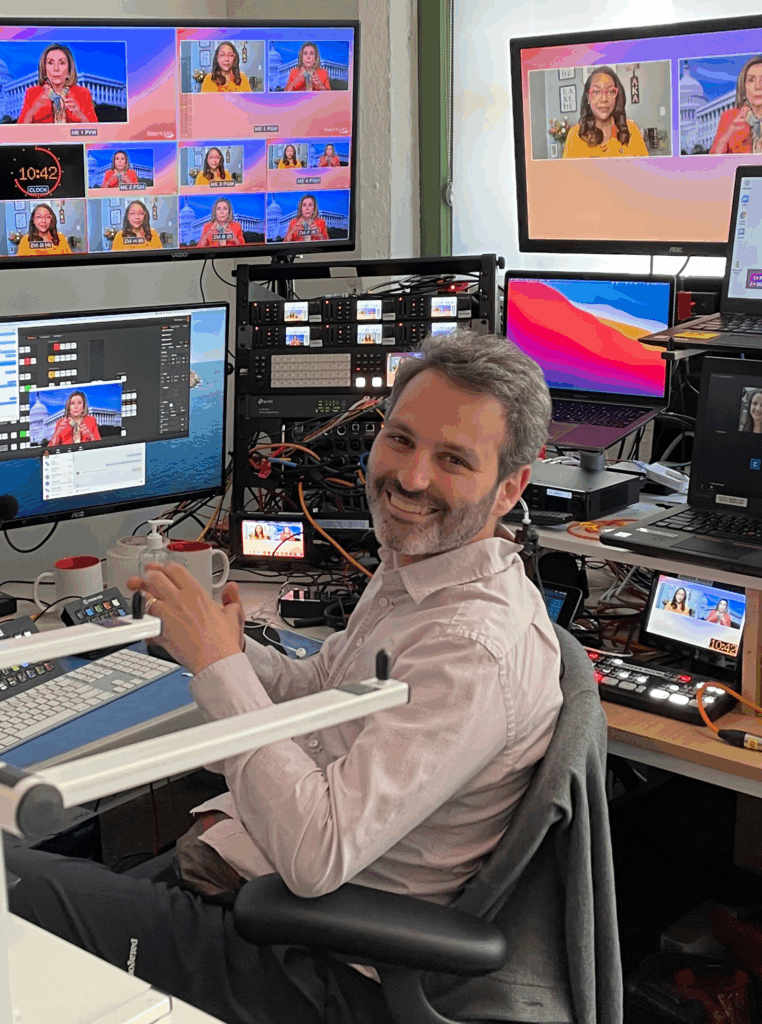 Livestream Technician Smiles at Camera while surrounded by broadcast equipment